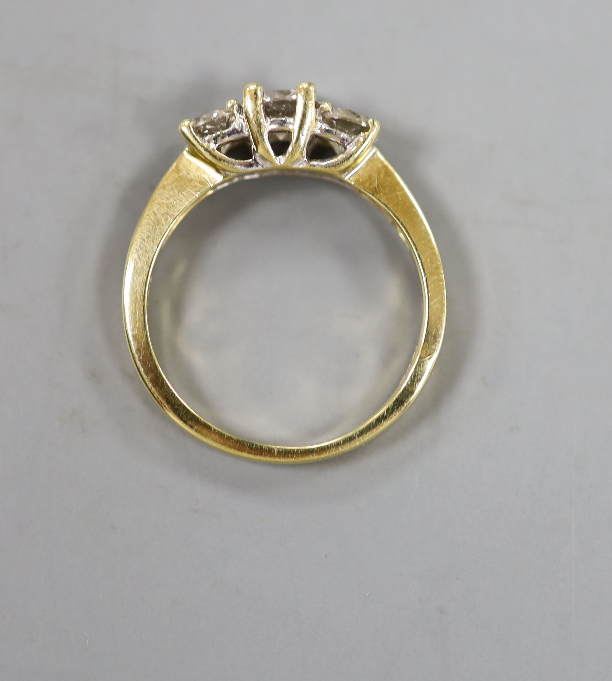 A modern 18ct gold and three stone diamond ring, size M, gross weight 3.4 grams.